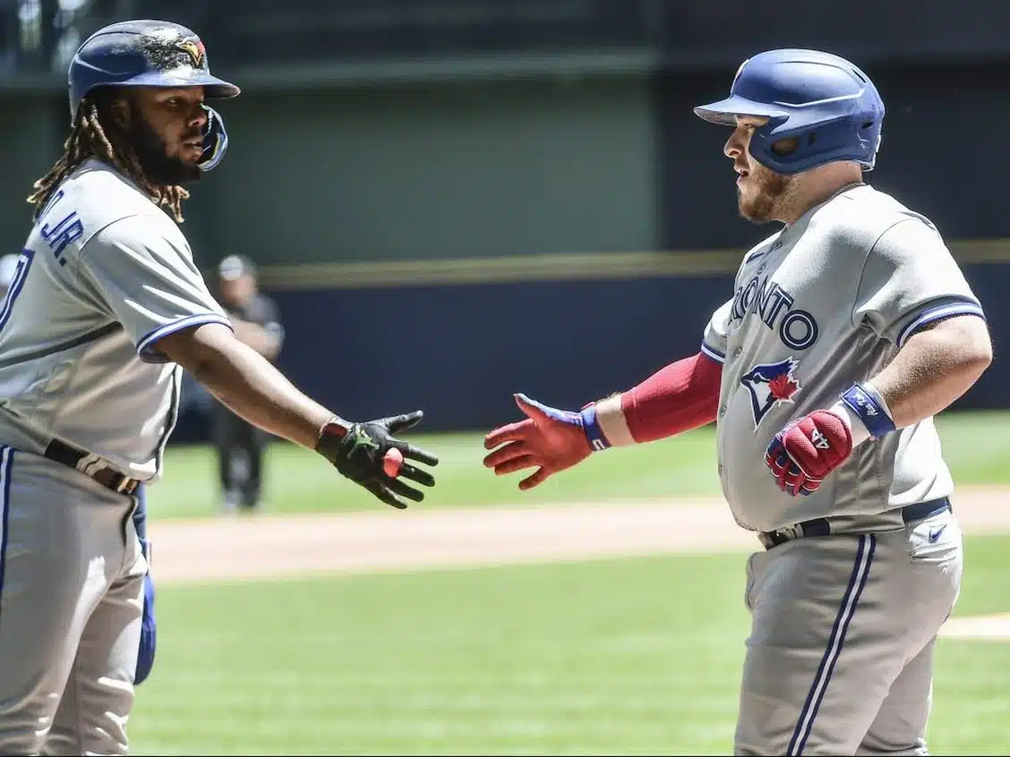 El receptor de los Toronto Blue Jays, Alejandro Kirk (derecha), es recibido por su compañero de equipo Vladimir Guerrero Jr. (izquierda) después de conectar un jonrón de tres carreras contra los Milwaukee Brewers.